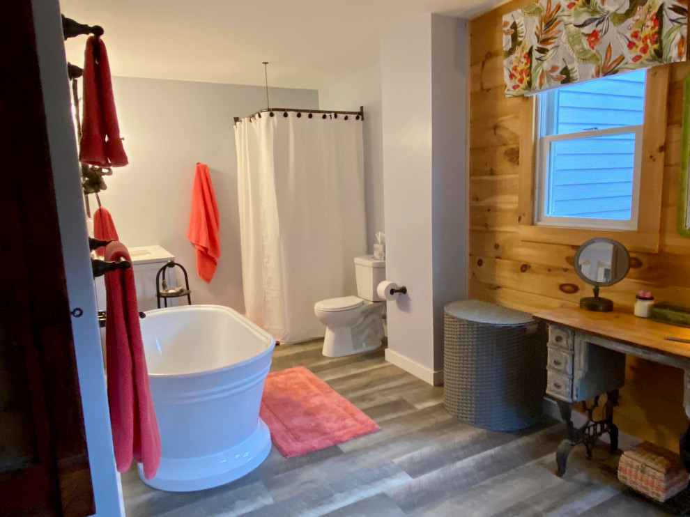 Bild på ett mellanstort eklektiskt vit vitt en-suite badrum, med luckor med infälld panel, vita skåp, ett fristående badkar, en hörndusch, en toalettstol med separat cisternkåpa, grå väggar, laminatgolv, ett integrerad handfat, bänkskiva i akrylsten, grått golv och dusch med duschdraperi