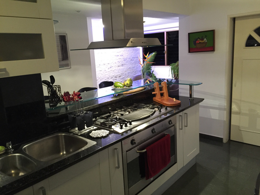 Transitional travertine floor and green floor eat-in kitchen photo with a triple-bowl sink, shaker cabinets, white cabinets, granite countertops, green backsplash, granite backsplash, stainless steel appliances and green countertops