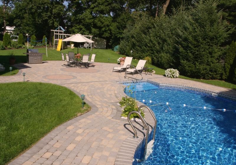 Inspiration for a mid-sized traditional backyard custom-shaped natural pool in New York with a water feature and natural stone pavers.