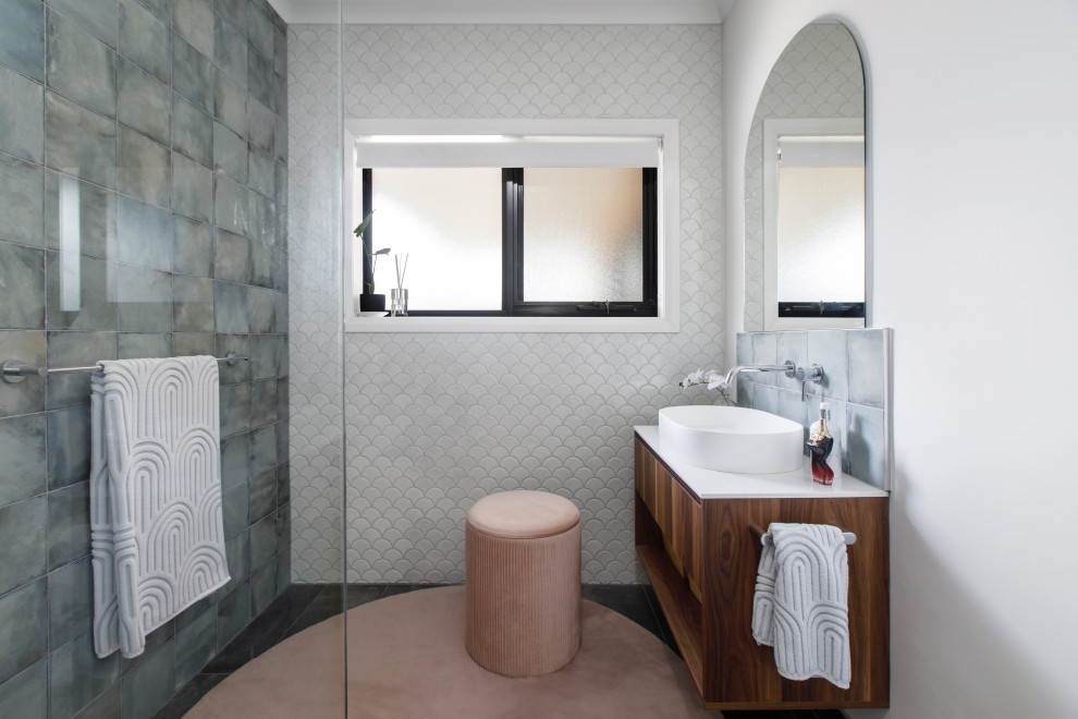 This is an example of a large contemporary master bathroom in Melbourne with flat-panel cabinets, medium wood cabinets, a curbless shower, blue tile, ceramic tile, solid surface benchtops, white benchtops, a single vanity and a floating vanity.
