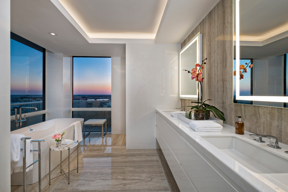 Mid-sized contemporary master bathroom in Miami with flat-panel cabinets, white cabinets, a freestanding tub, brown tile, white walls, an undermount sink, brown floor, white benchtops and engineered quartz benchtops.