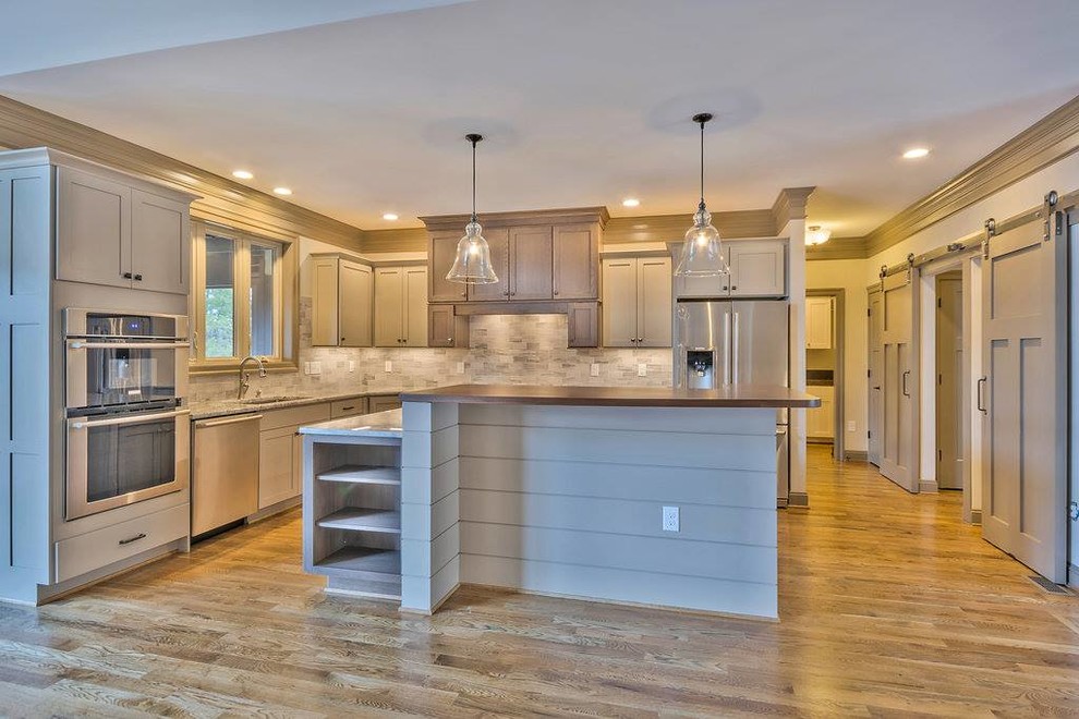 Mid-sized medium tone wood floor kitchen photo with shaker cabinets, gray cabinets, granite countertops, gray backsplash, stainless steel appliances and an island