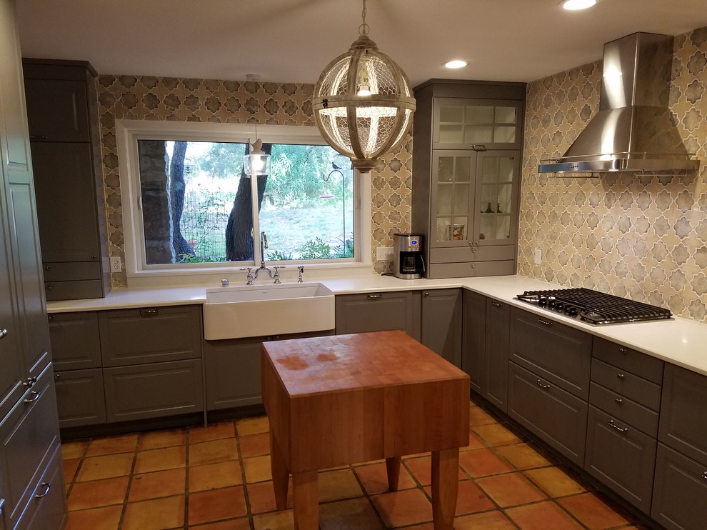Mid-sized arts and crafts l-shaped separate kitchen in Austin with a farmhouse sink, raised-panel cabinets, grey cabinets, quartzite benchtops, multi-coloured splashback, ceramic splashback, stainless steel appliances, terra-cotta floors, no island and brown floor.