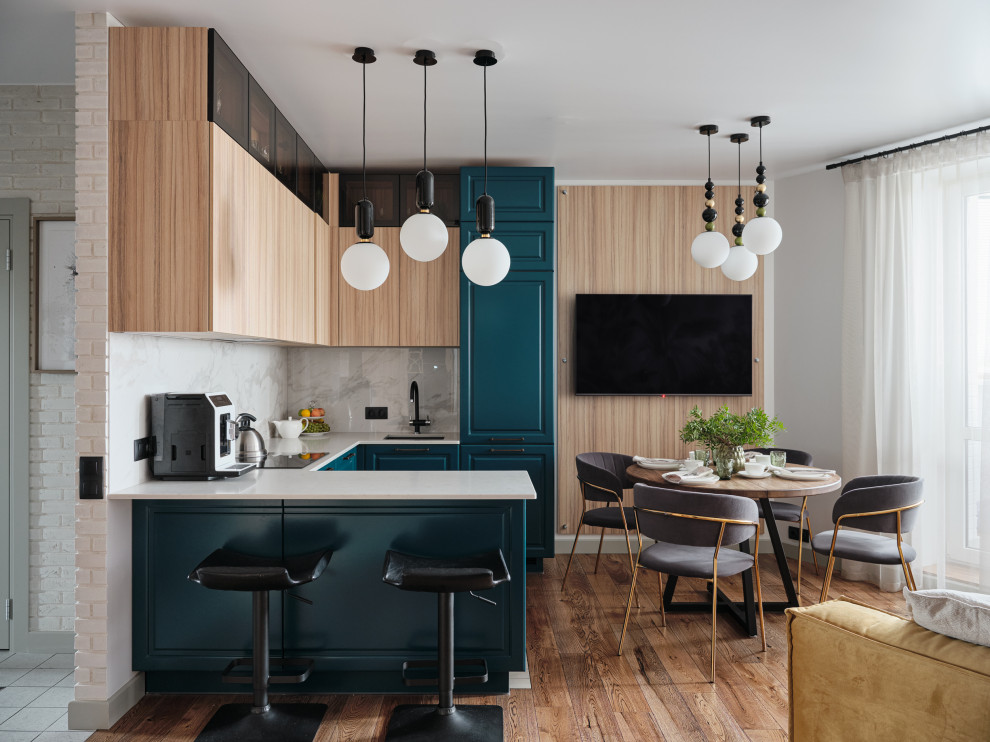 Cette photo montre une cuisine ouverte bicolore tendance en U avec un évier encastré, un sol en bois brun, aucun îlot, un sol marron et un plan de travail blanc.