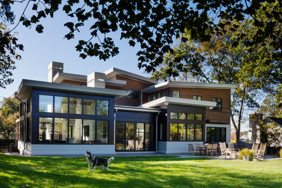 Стильный дизайн: большой, двухэтажный, коричневый частный загородный дом в стиле модернизм с комбинированной облицовкой, крышей-бабочкой, металлической крышей и черной крышей - последний тренд