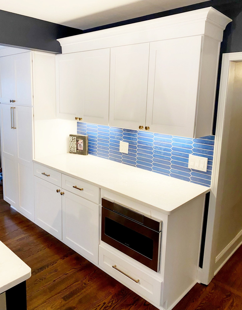 Mid-sized traditional u-shaped kitchen in Detroit with an undermount sink, shaker cabinets, white cabinets, granite benchtops, blue splashback, glass tile splashback, stainless steel appliances, medium hardwood floors, with island, brown floor and white benchtop.