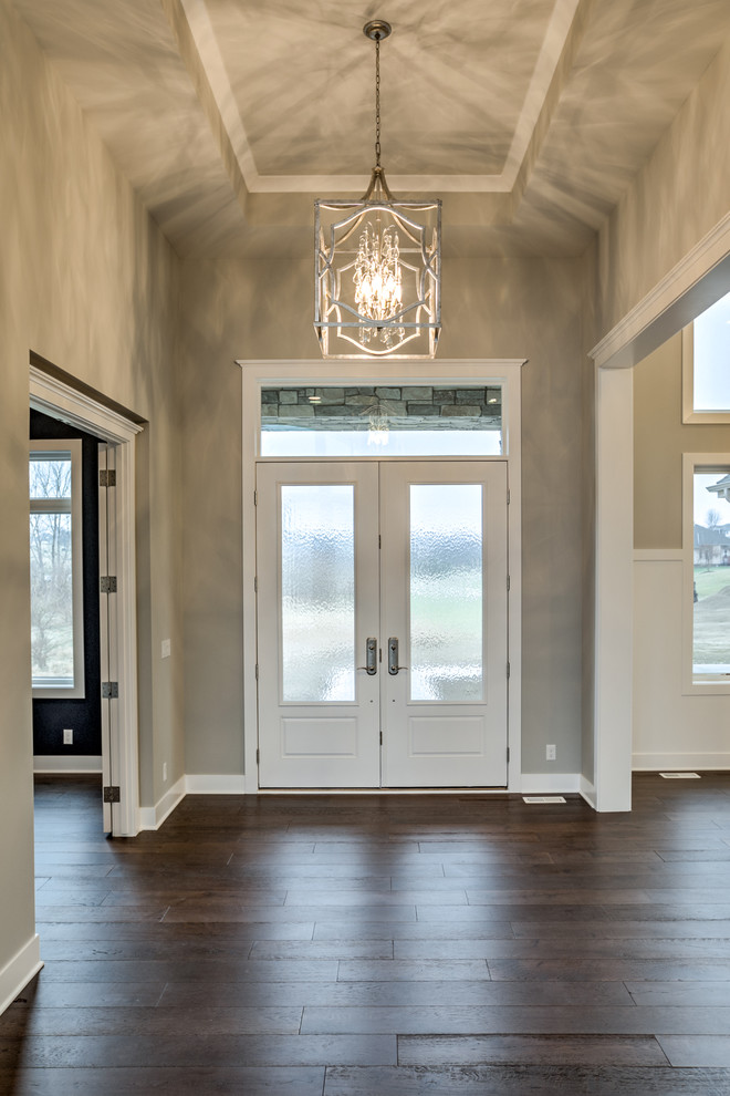 Design ideas for a large country front door in Omaha with dark hardwood floors, a double front door, beige walls, a white front door and brown floor.
