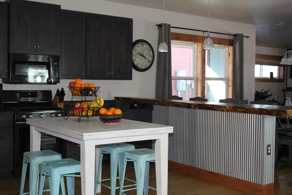Large transitional u-shaped light wood floor and brown floor open concept kitchen photo with shaker cabinets, dark wood cabinets, an island and black countertops