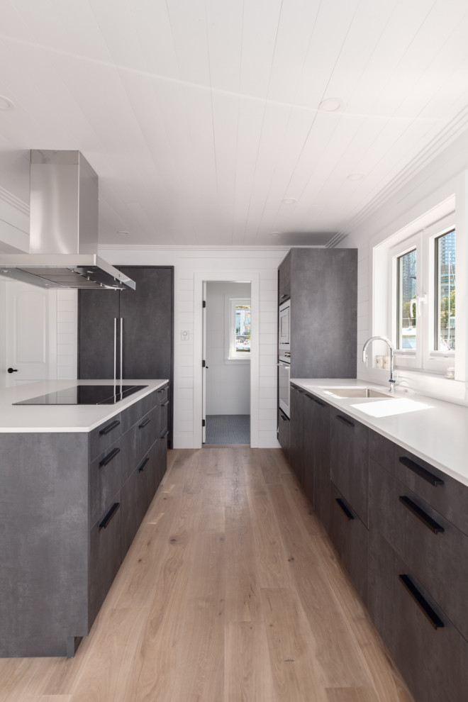 Photo of a mid-sized arts and crafts u-shaped open plan kitchen in Vancouver with an undermount sink, flat-panel cabinets, distressed cabinets, quartz benchtops, white splashback, timber splashback, stainless steel appliances, medium hardwood floors, with island and white benchtop.