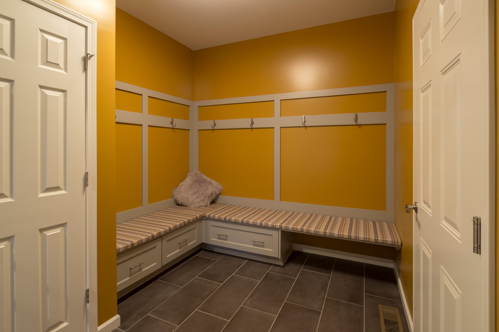 Design ideas for a mid-sized traditional mudroom in New York with yellow walls, ceramic floors and grey floor.