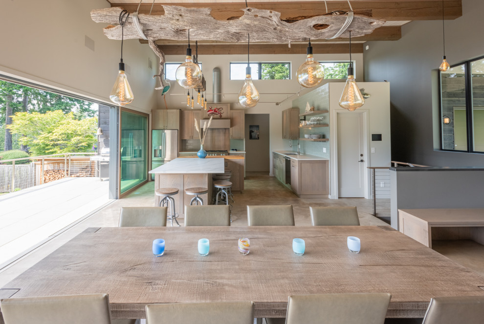 Cette image montre une salle à manger ouverte sur le salon minimaliste en bois de taille moyenne avec un mur blanc, sol en béton ciré, une cheminée double-face, un manteau de cheminée en métal, un sol gris et poutres apparentes.