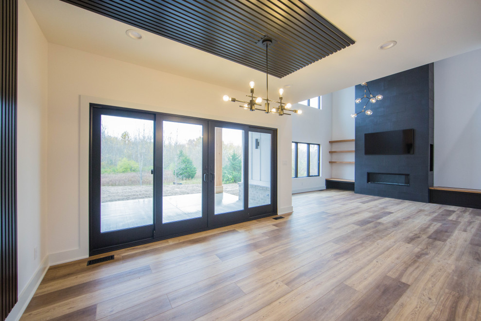 Große Moderne Wohnküche mit weißer Wandfarbe, braunem Holzboden, Kamin, gefliester Kaminumrandung, braunem Boden, Holzdecke und Holzwänden in Indianapolis