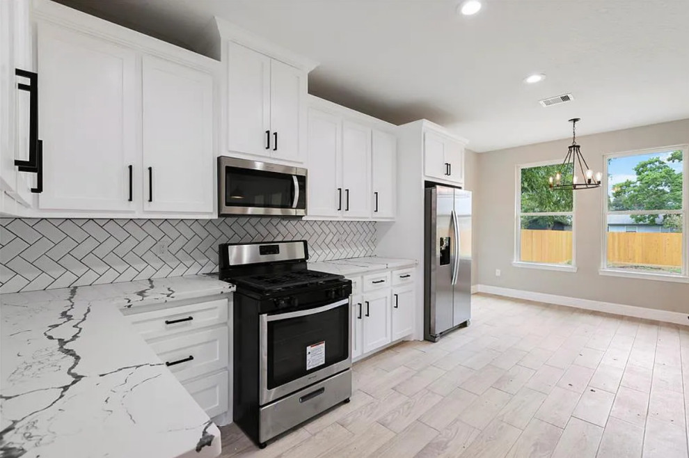 Example of a mid-sized transitional l-shaped porcelain tile, beige floor and coffered ceiling eat-in kitchen design in Houston with a drop-in sink, shaker cabinets, white cabinets, quartzite countertops, white backsplash, ceramic backsplash, black appliances, an island and white countertops
