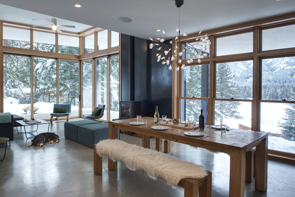 Photo of a mid-sized contemporary open plan dining in Seattle with white walls, concrete floors, a wood stove, a metal fireplace surround and grey floor.