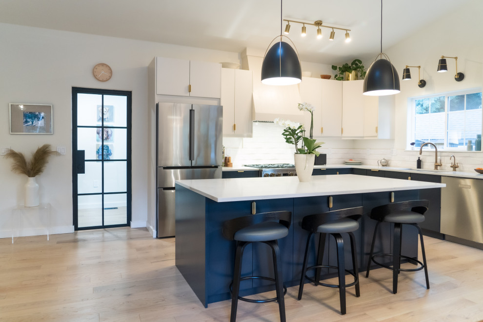 Photo of a large scandinavian l-shaped eat-in kitchen in Seattle with an undermount sink, flat-panel cabinets, blue cabinets, quartz benchtops, stainless steel appliances, light hardwood floors, with island, beige floor, white benchtop and vaulted.