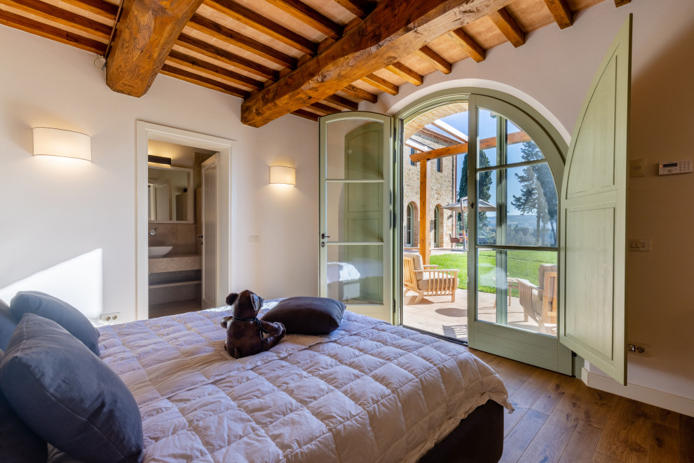 Großes Country Gästezimmer mit beiger Wandfarbe, gebeiztem Holzboden, braunem Boden und freigelegten Dachbalken in Florenz