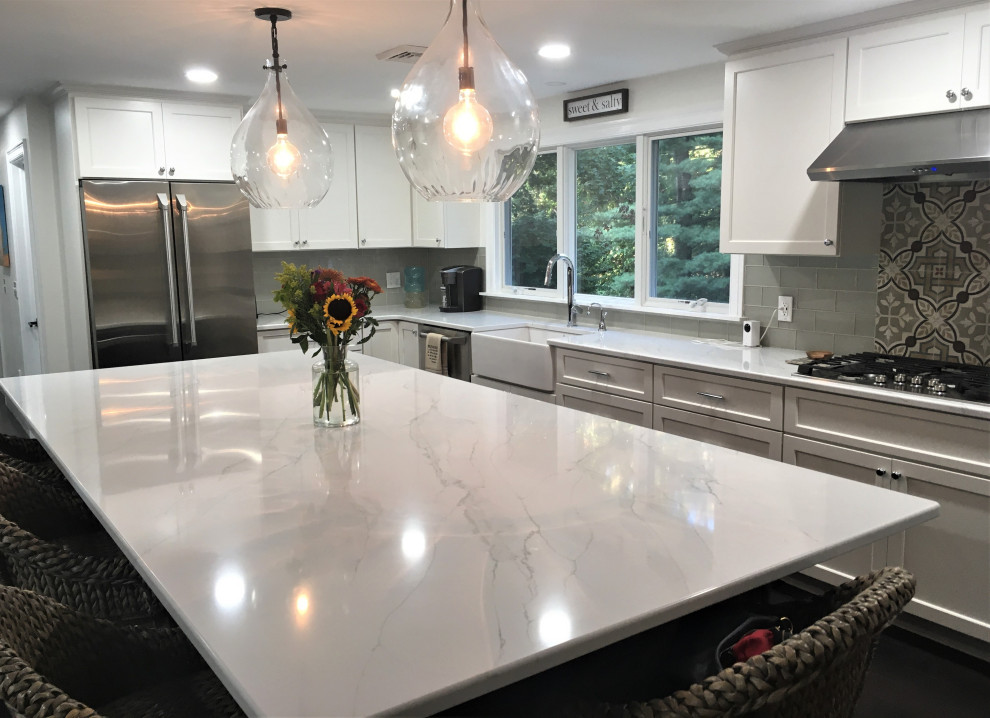 Huge transitional l-shaped dark wood floor and brown floor eat-in kitchen photo in Boston with a farmhouse sink, shaker cabinets, white cabinets, quartz countertops, gray backsplash, subway tile backsplash, stainless steel appliances, an island and white countertops