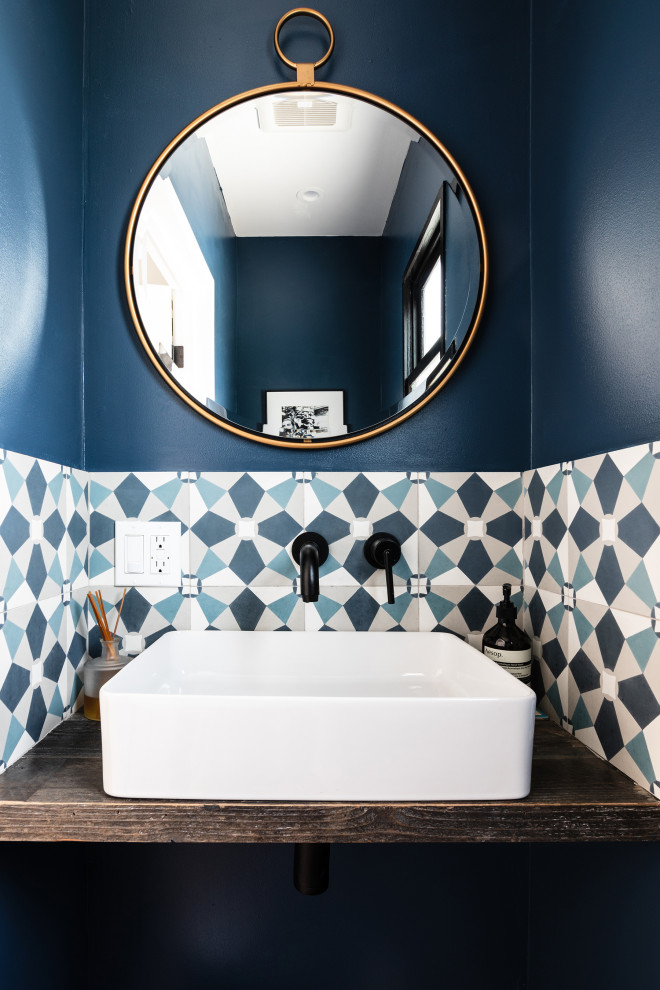 This is an example of a small mediterranean powder room in Los Angeles with blue walls, a vessel sink and a floating vanity.