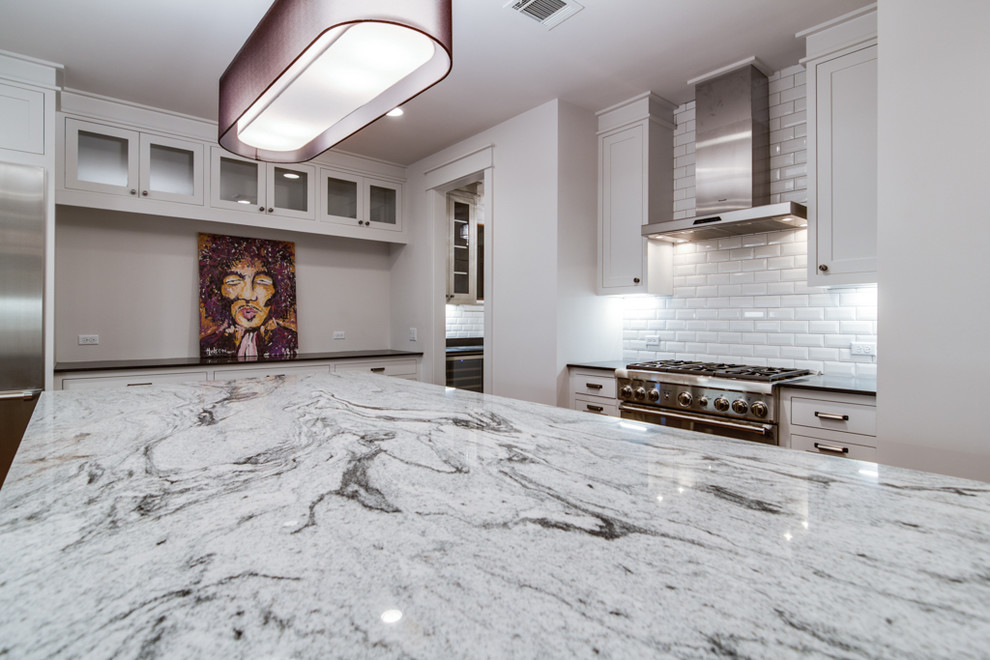 This is an example of a large transitional u-shaped open plan kitchen in Houston with an undermount sink, shaker cabinets, white cabinets, granite benchtops, white splashback, subway tile splashback, stainless steel appliances, dark hardwood floors, with island and brown floor.