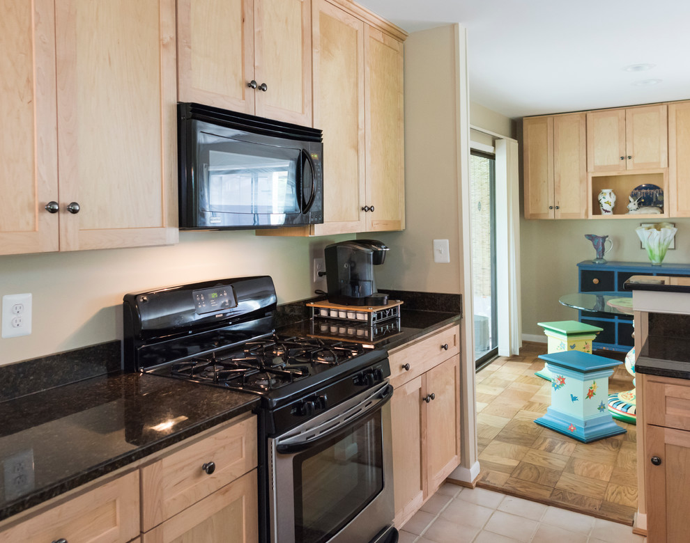 Example of a small transitional galley porcelain tile eat-in kitchen design in DC Metro with an undermount sink, flat-panel cabinets, light wood cabinets, granite countertops, black backsplash, stainless steel appliances and no island