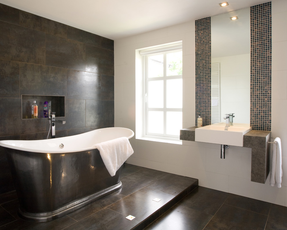 Inspiration for a large contemporary master bathroom in Sussex with a freestanding tub, a wall-mount toilet, brown tile, porcelain tile, brown walls, porcelain floors, a wall-mount sink, open cabinets, grey cabinets, an open shower, granite benchtops, brown floor, an open shower and grey benchtops.