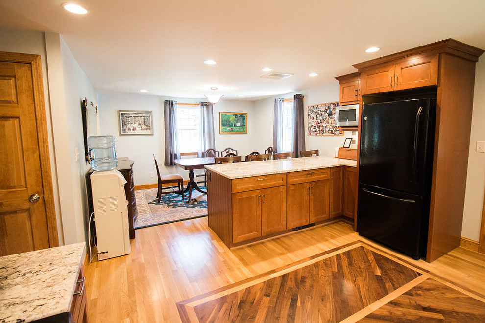 Mid-sized transitional u-shaped medium tone wood floor eat-in kitchen photo in Boston with an undermount sink, recessed-panel cabinets, medium tone wood cabinets, granite countertops, multicolored backsplash, subway tile backsplash, black appliances and a peninsula