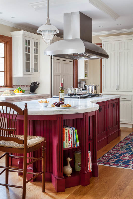 This is an example of a traditional eat-in kitchen in Boston with a farmhouse sink, beaded inset cabinets, red cabinets, marble benchtops, white splashback, stone slab splashback, panelled appliances, medium hardwood floors and with island.