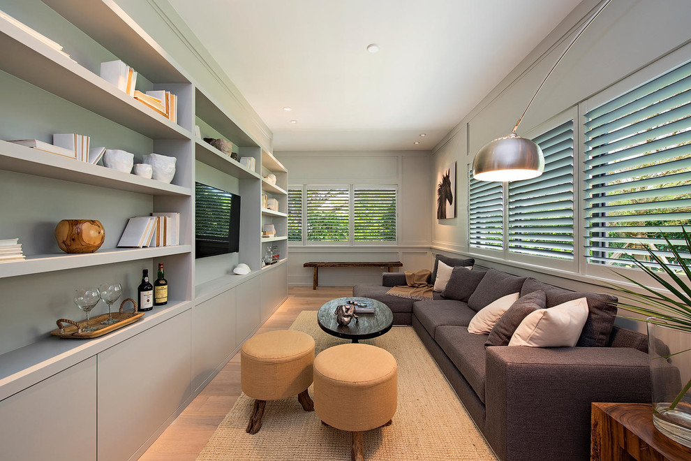 Contemporary living room in Miami with grey walls, light hardwood floors and a wall-mounted tv.
