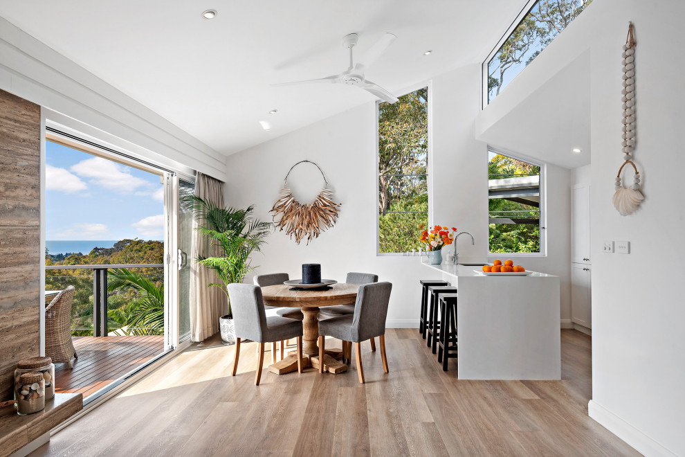 Photo of a beach style open plan dining in Sydney with white walls, medium hardwood floors, brown floor and vaulted.