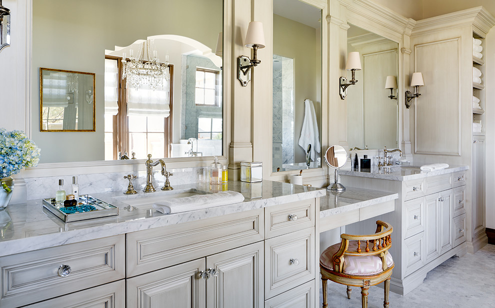 This is an example of a transitional master bathroom in Phoenix with an undermount sink, furniture-like cabinets, grey cabinets, marble benchtops, a freestanding tub, gray tile, stone tile, beige walls and marble floors.