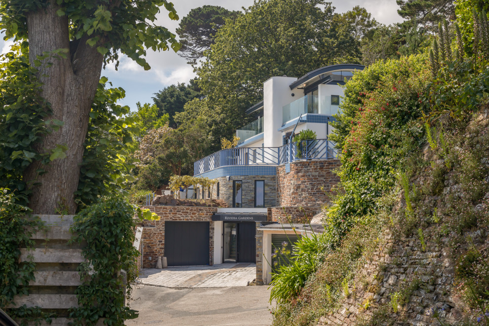 Inspiration for a large beach style split-level front detached house in Cornwall with stone cladding and a metal roof.