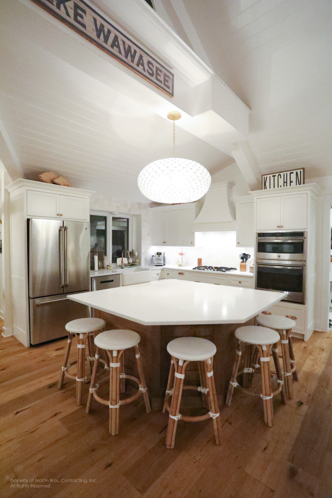 Mid-sized beach style l-shaped medium tone wood floor and shiplap ceiling open concept kitchen photo in Other with a farmhouse sink, beaded inset cabinets, white cabinets, quartz countertops, white backsplash, ceramic backsplash, stainless steel appliances, an island and white countertops