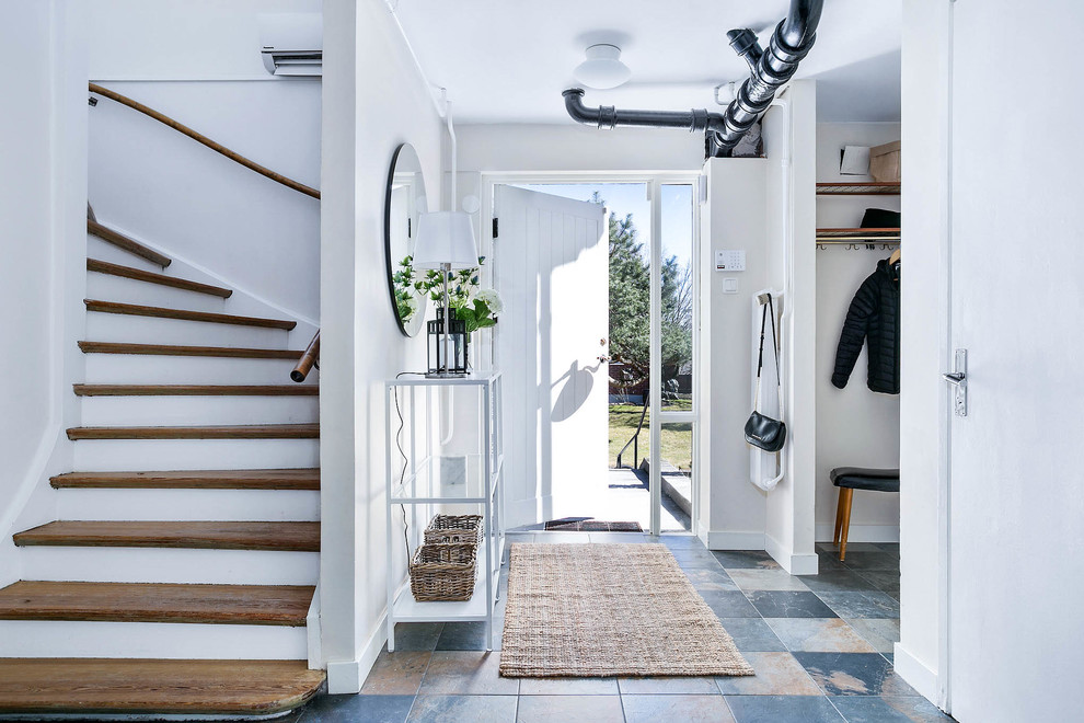 Photo of a mid-sized scandinavian entryway in Gothenburg with white walls and multi-coloured floor.