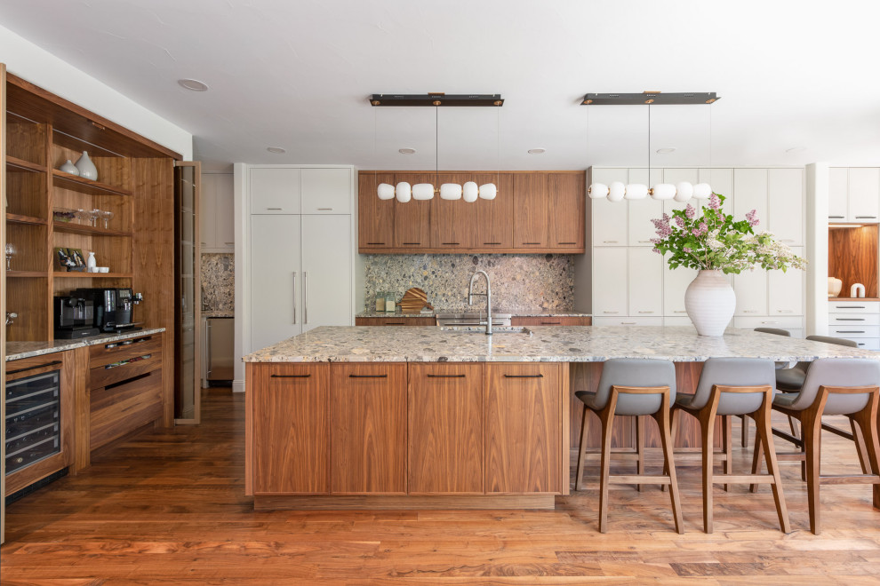 This is an example of a large contemporary l-shaped open plan kitchen in Denver with an undermount sink, flat-panel cabinets, medium wood cabinets, terrazzo benchtops, grey splashback, stone slab splashback, panelled appliances, medium hardwood floors, with island, brown floor and grey benchtop.