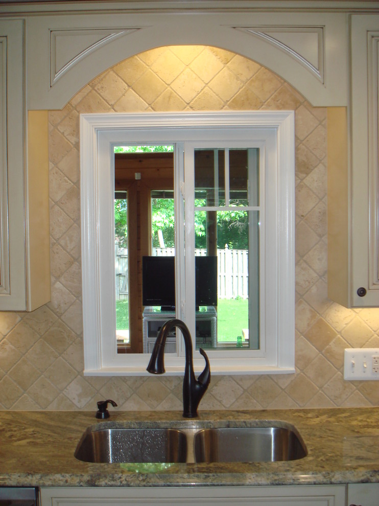 Inspiration for a kitchen remodel in Baltimore with a double-bowl sink, raised-panel cabinets, granite countertops, beige backsplash and stone tile backsplash