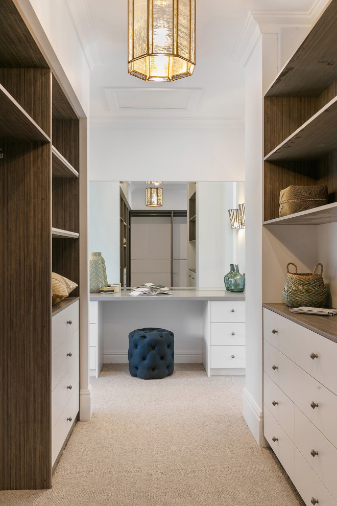 This is an example of a large beach style gender-neutral walk-in wardrobe in Sydney with open cabinets, medium wood cabinets, carpet and beige floor.