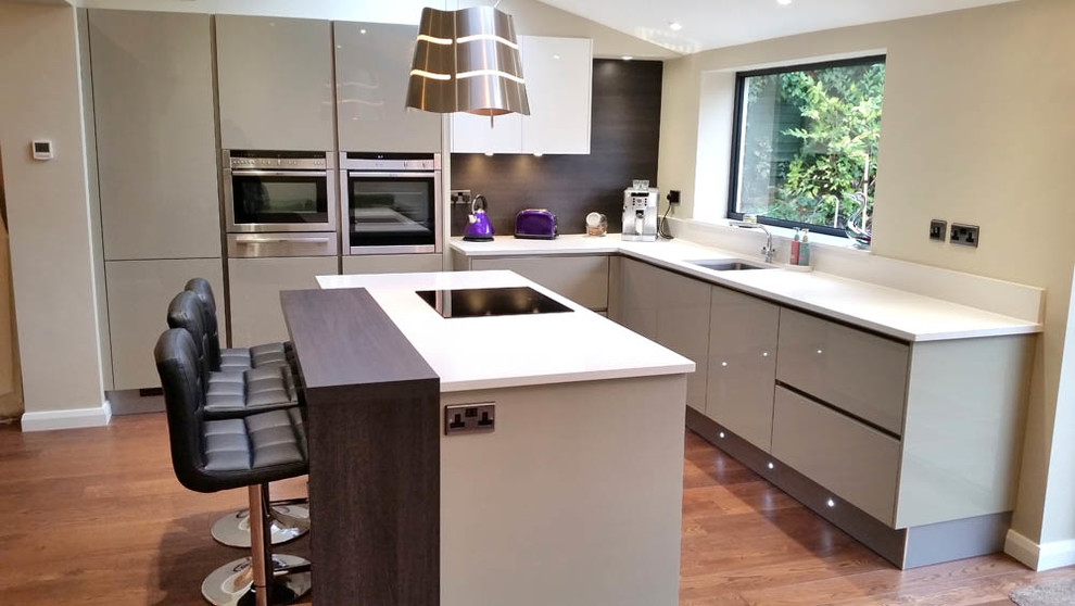 Mid-sized contemporary l-shaped eat-in kitchen in Other with a single-bowl sink, flat-panel cabinets, grey cabinets, solid surface benchtops, brown splashback, stainless steel appliances, dark hardwood floors and with island.