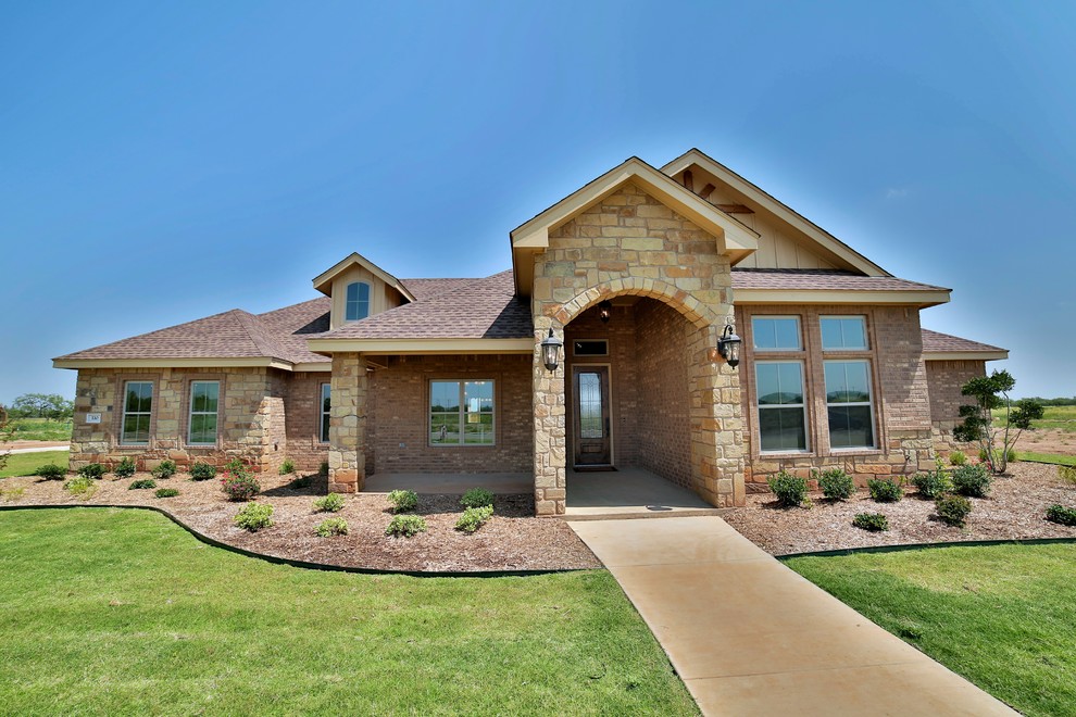 This is an example of a large transitional one-storey beige exterior in Austin with stone veneer.