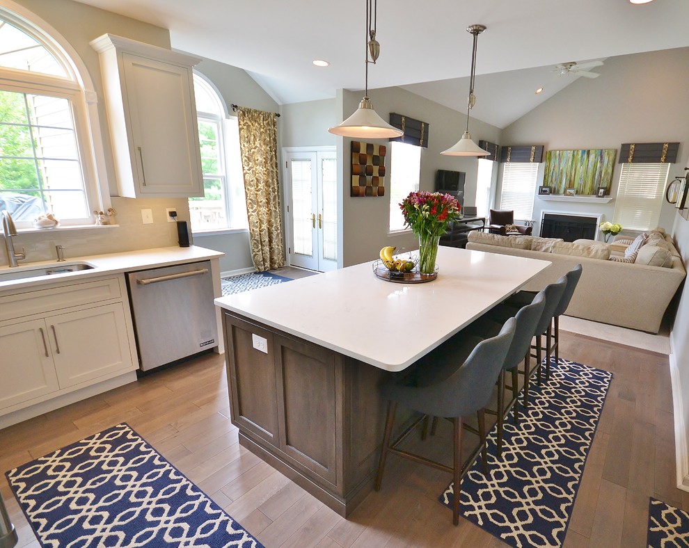 Inspiration for a large transitional l-shaped eat-in kitchen in Philadelphia with an undermount sink, recessed-panel cabinets, white cabinets, quartz benchtops, grey splashback, ceramic splashback, stainless steel appliances, medium hardwood floors, with island and beige floor.