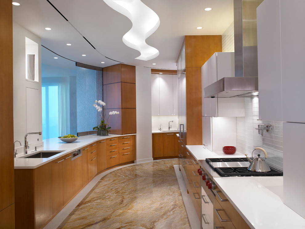 Photo of a large contemporary galley separate kitchen in Miami with an undermount sink, flat-panel cabinets, medium wood cabinets, solid surface benchtops, white splashback, glass tile splashback, marble floors, no island and brown floor.