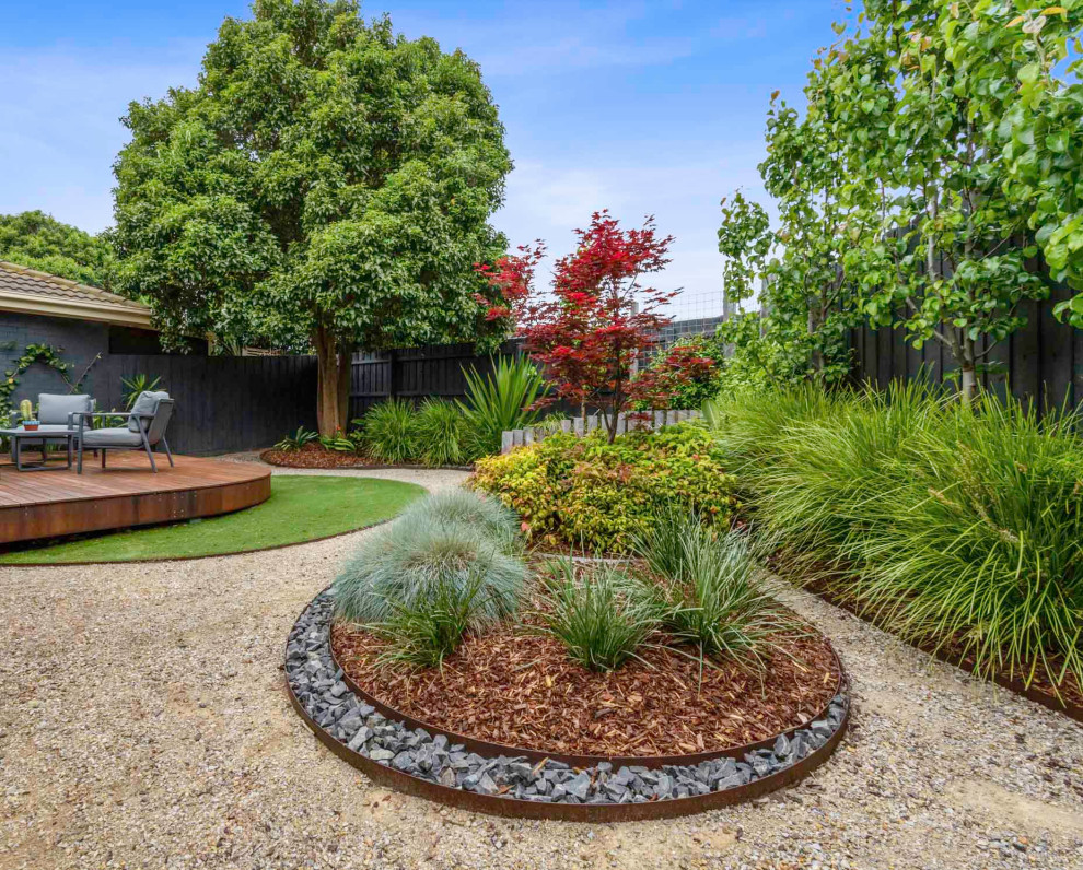 Immagine di un grande giardino xeriscape minimalista esposto in pieno sole dietro casa in primavera con un focolare, pedane e recinzione in legno
