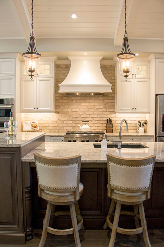Example of a large transitional l-shaped eat-in kitchen design with a double-bowl sink, shaker cabinets, white cabinets, beige backsplash, stainless steel appliances and an island