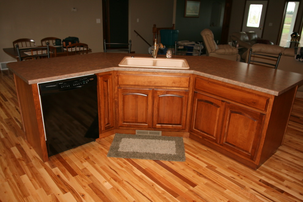 Inspiration for a mid-sized l-shaped light wood floor open concept kitchen remodel with a drop-in sink, raised-panel cabinets, medium tone wood cabinets, laminate countertops, stainless steel appliances and an island