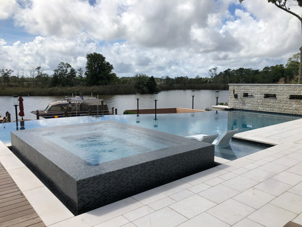 Modelo de casa de la piscina y piscina infinita minimalista de tamaño medio rectangular en patio trasero con adoquines de piedra natural