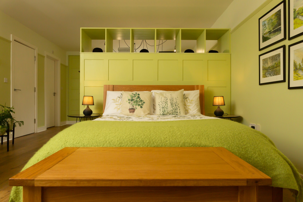 Imagen de dormitorio principal y blanco de tamaño medio con paredes verdes, suelo laminado y suelo marrón