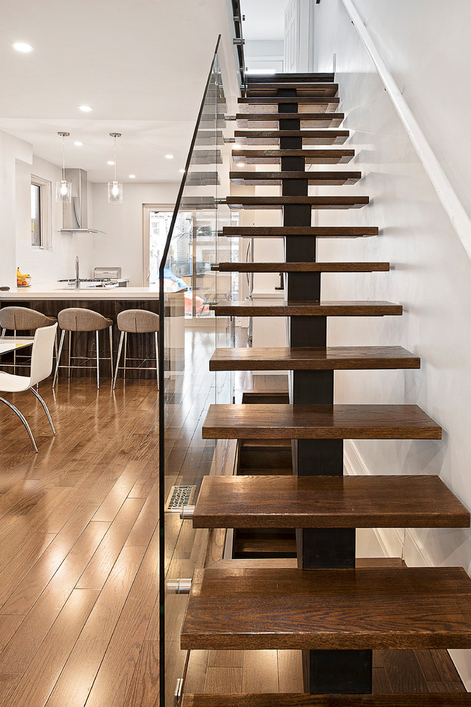 Photo of a mid-sized contemporary wood straight staircase in Toronto with open risers and glass railing.
