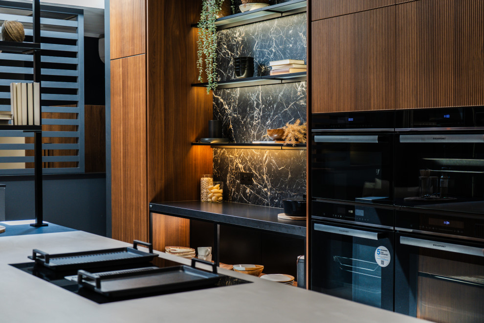 Design ideas for a medium sized modern l-shaped open plan kitchen in London with a built-in sink, glass-front cabinets, black cabinets, marble worktops, black splashback, stone slab splashback, black appliances, porcelain flooring, an island, grey floors and black worktops.