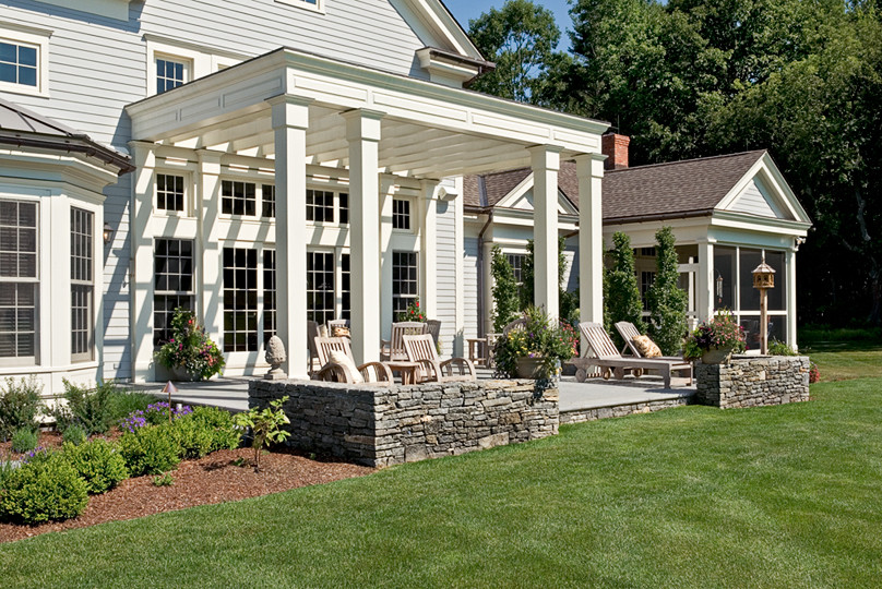 This is an example of a large traditional front yard verandah in Boston with concrete slab and a pergola.