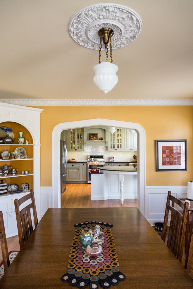 Photo of a large country separate dining room in Wichita with yellow walls, medium hardwood floors, no fireplace and brown floor.