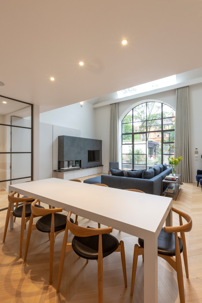 Large contemporary open plan dining in London with white walls, light hardwood floors and beige floor.